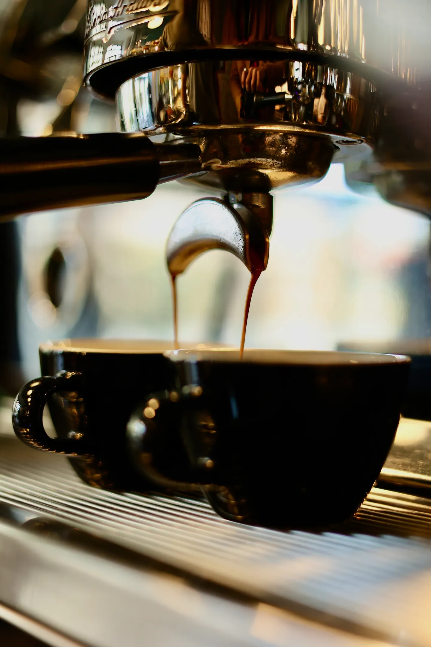 Espresso teče z kávovaru do dvou šálků